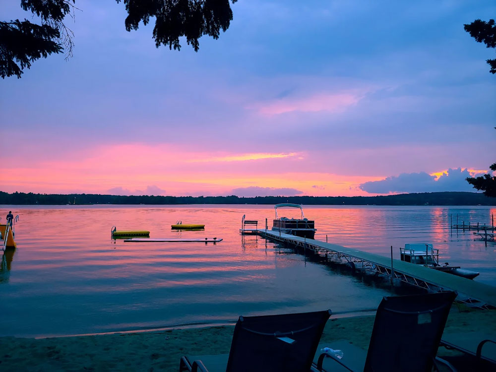 Sunset over calm lake with dock and boat