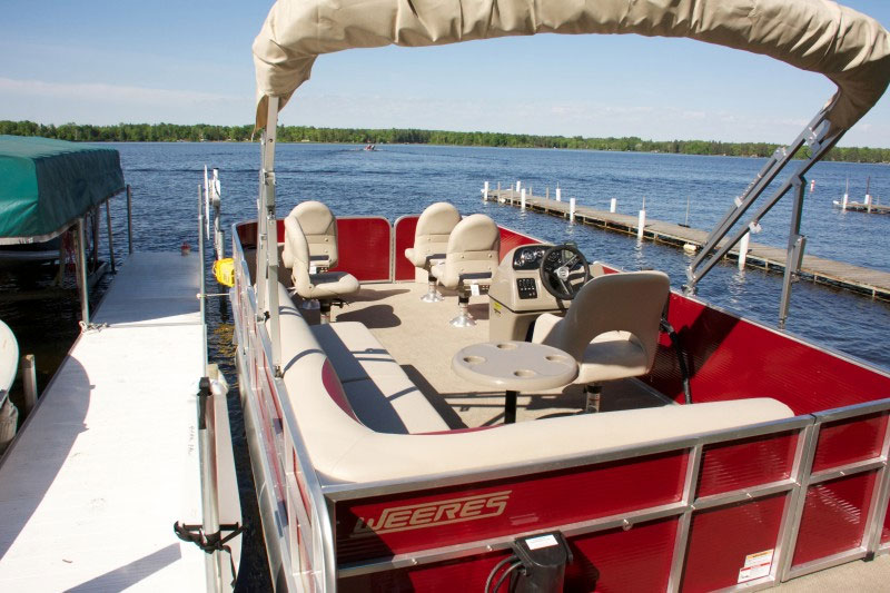 Red pontoon boat docked at lakeside marina