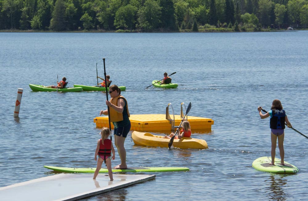 Families paddleboarding and kayaking on calm lake