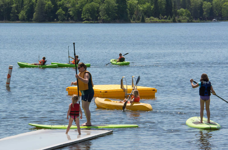 Family paddleboarding and kayaking on a calm lake