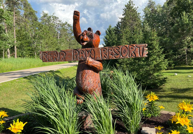 Wooden bear statue holding Bear Paw Resortz sign